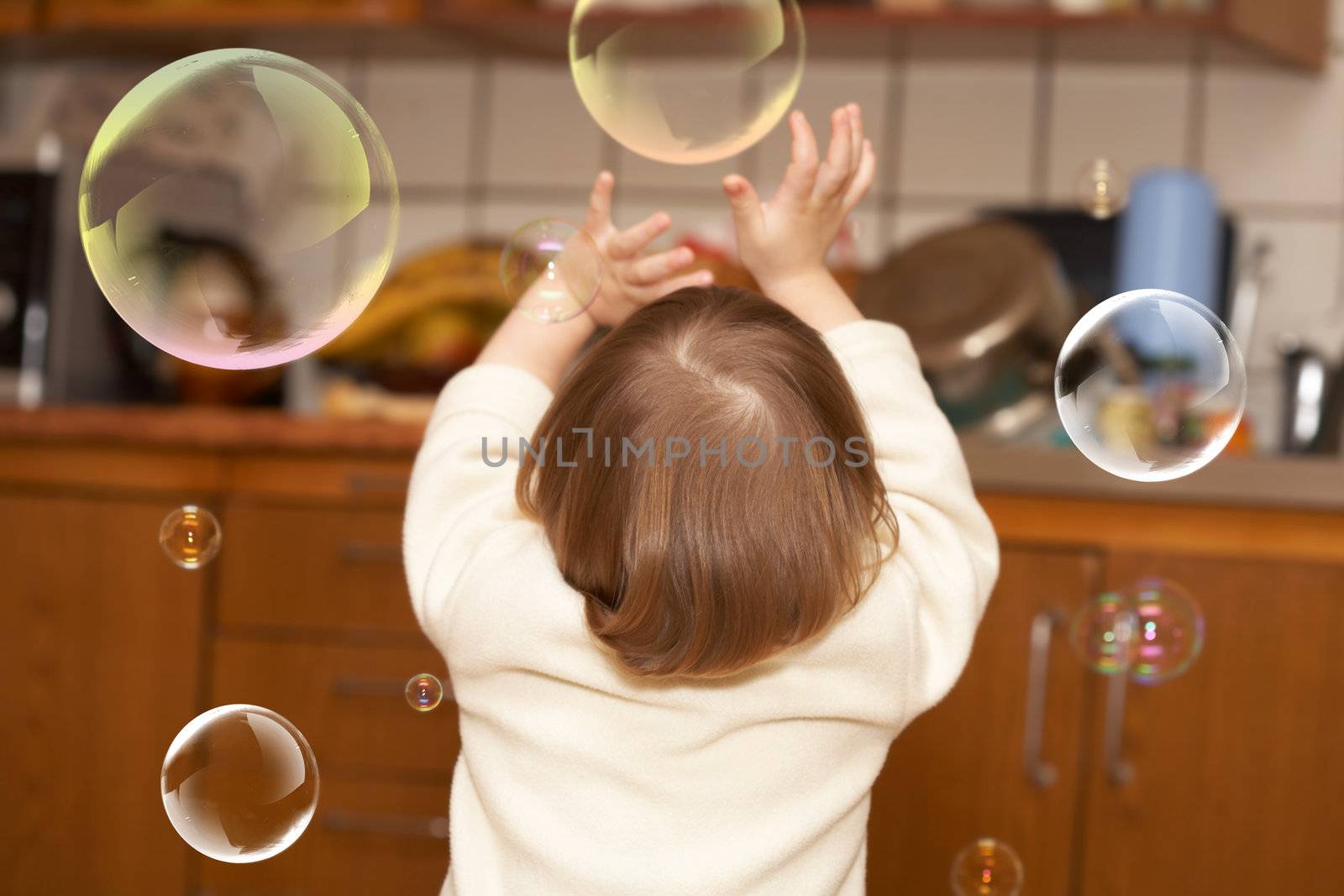 The small girl plays with soap bubbles. Childhood