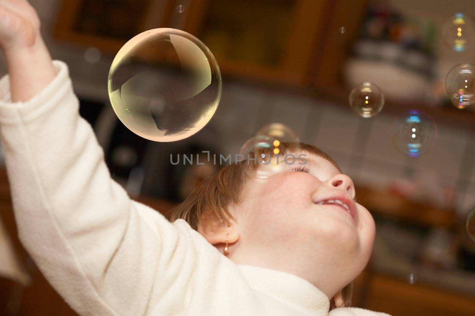 The small girl plays with soap bubbles. Childhood