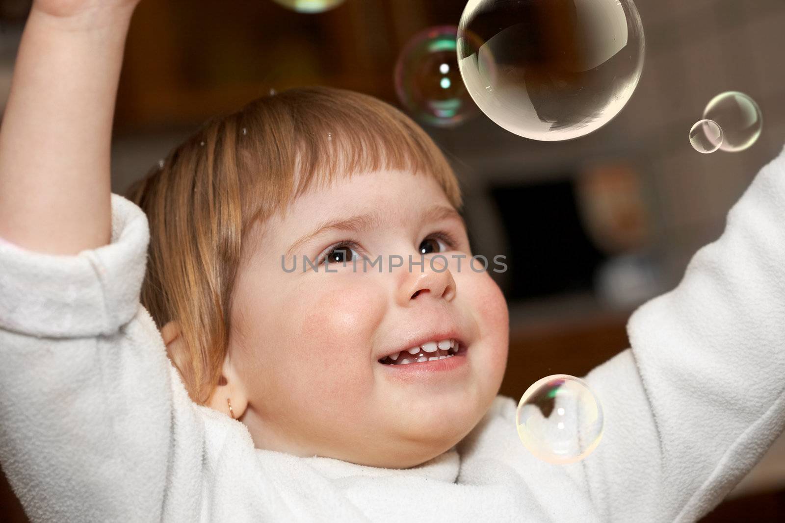 Joy. The small girl in a room plays with soap bubbles