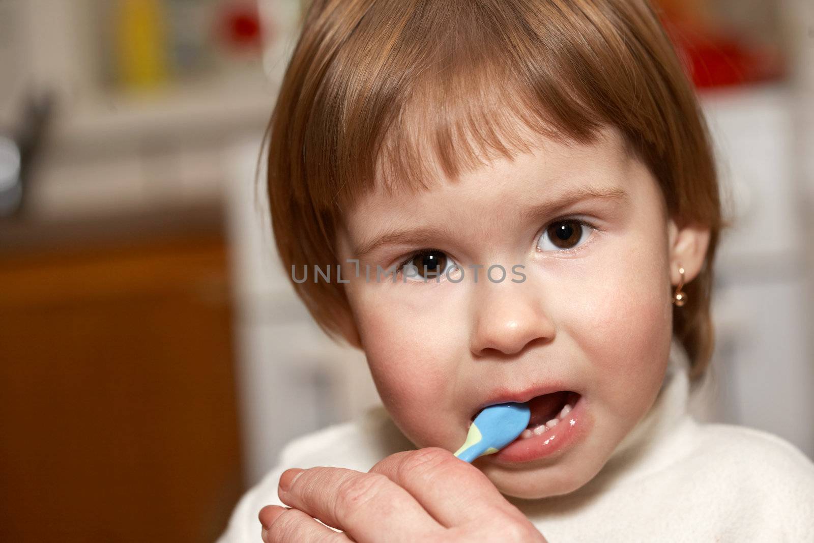 The small girl cleans teeth in a room