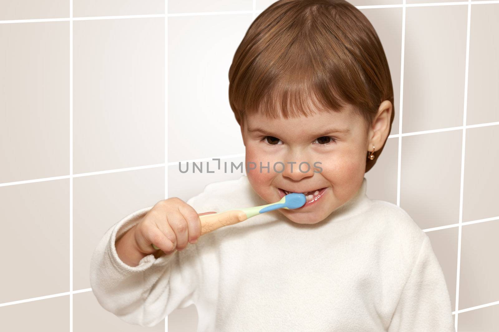 The small girl cleans teeth in a light bathroom