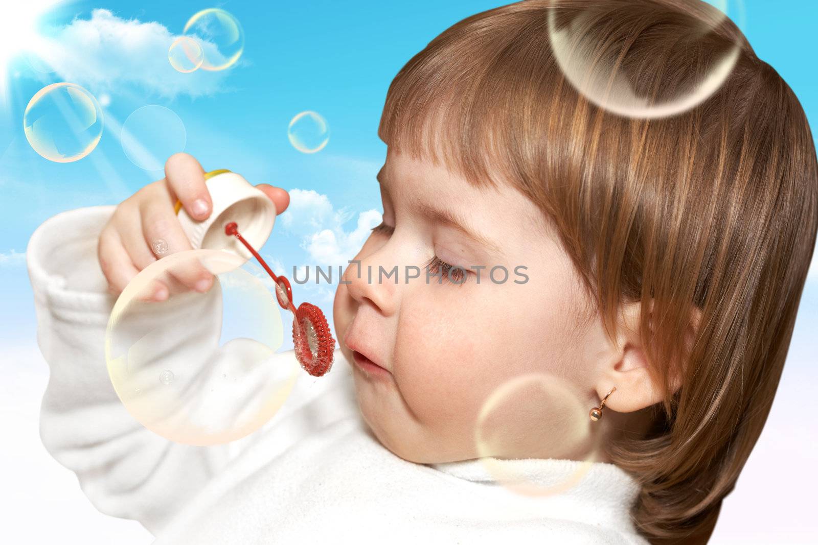 Soap bubbles. The small girl plays with soap bubbles