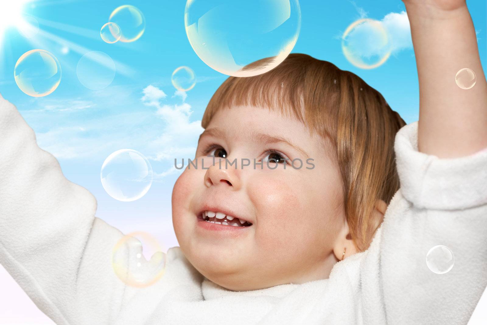 Joy. The small girl plays with soap bubbles