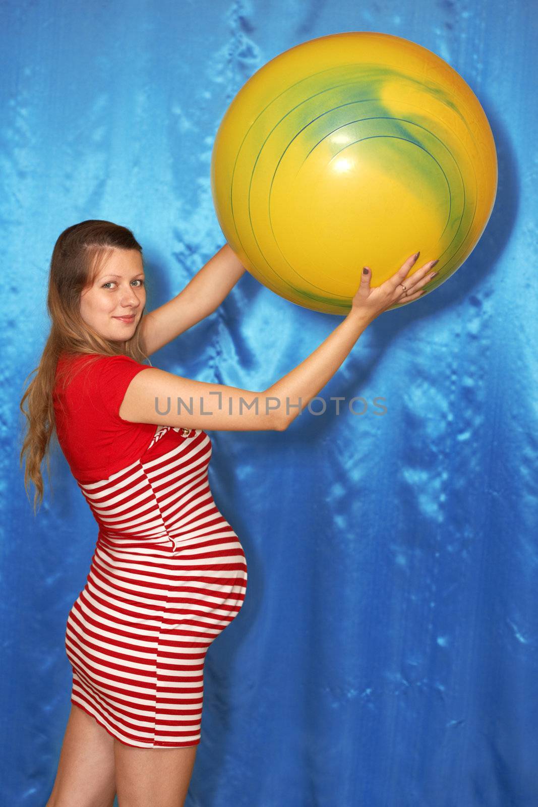 A pregnant woman and yellow ball on a blue background