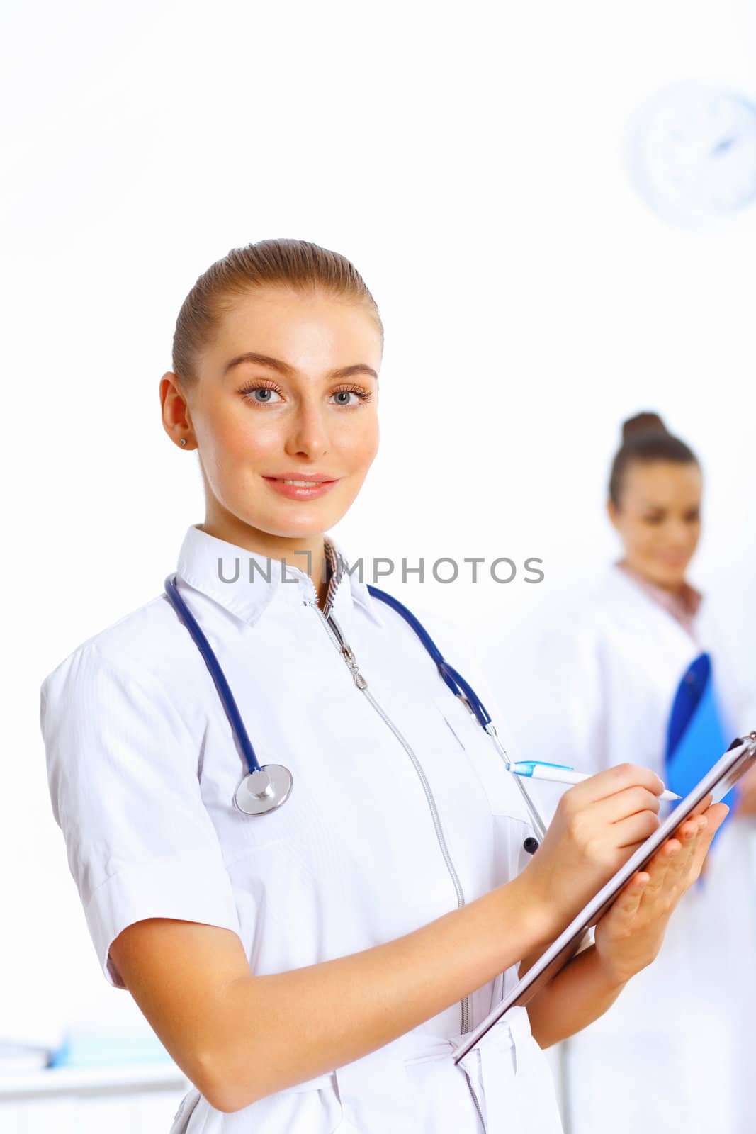 Young female doctor in white uniform with collegues on the background