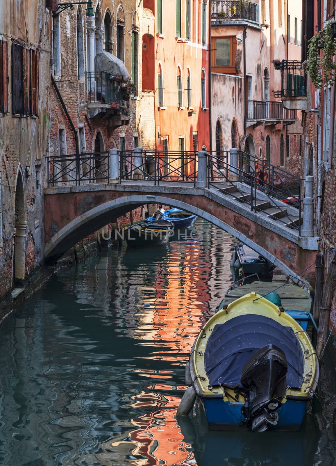 Motorboats parked near specific walls of houses on a small canal in Venice