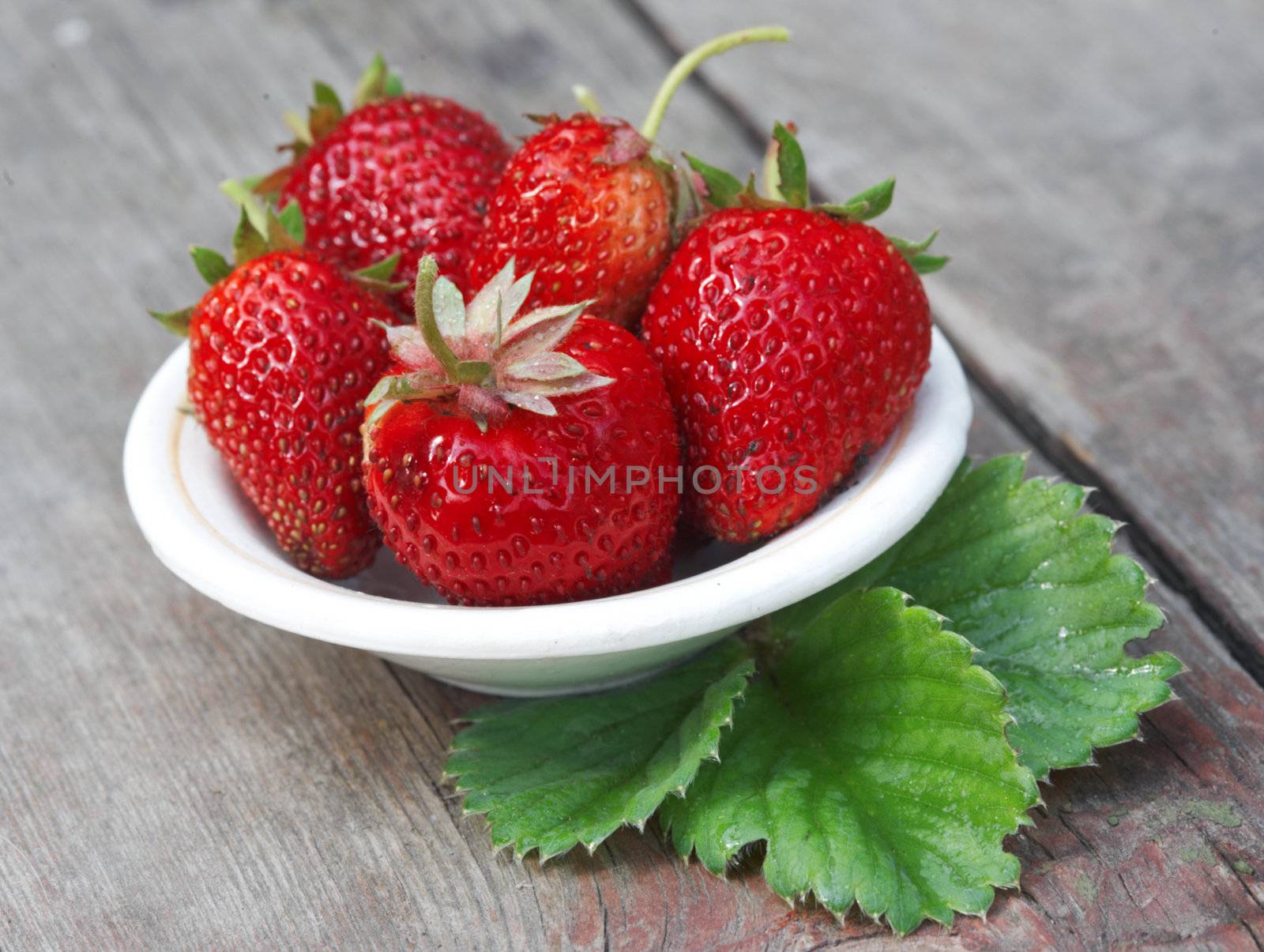 Wild strawberry in saucer on a wooden table