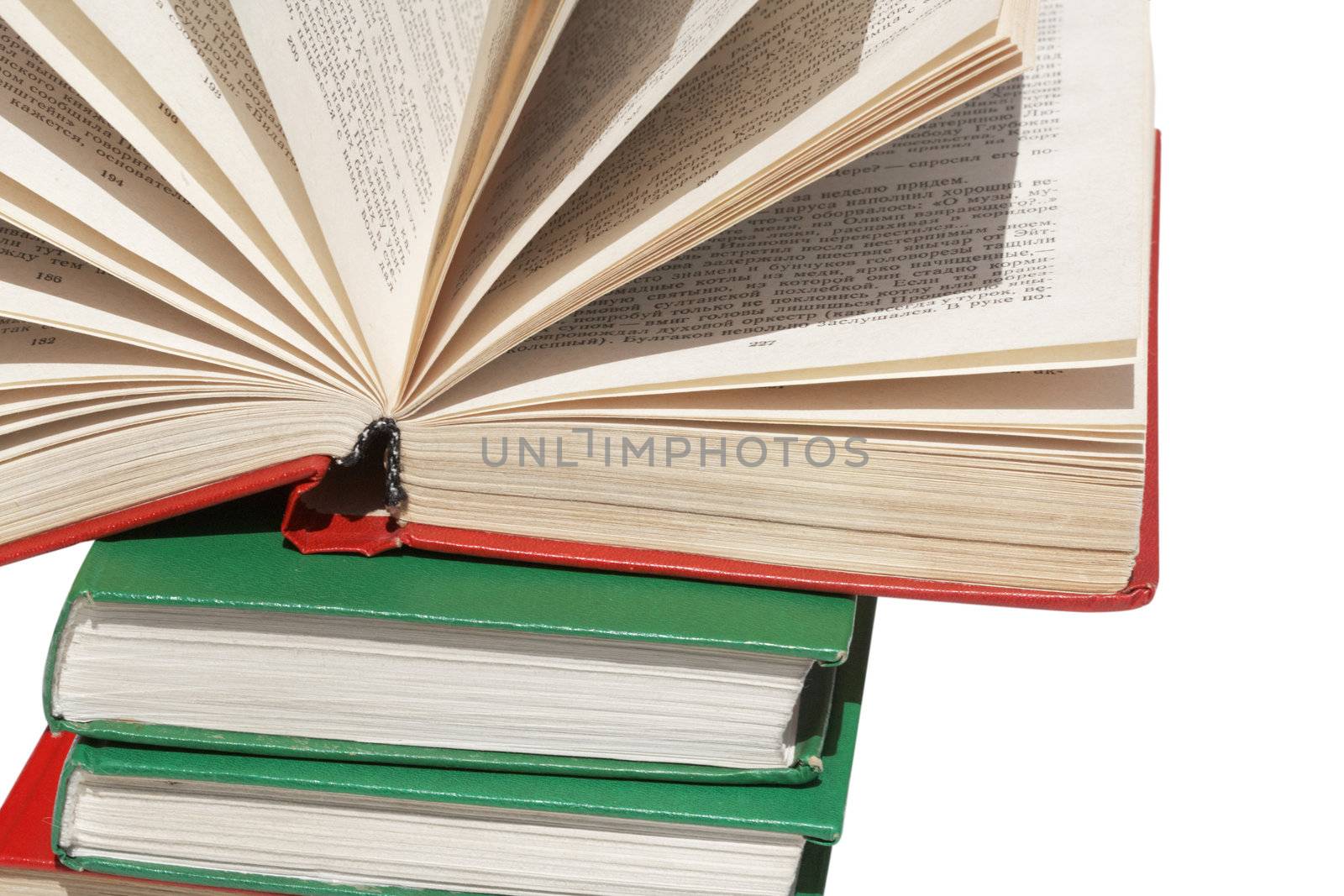 Pile of books with one book open on white background