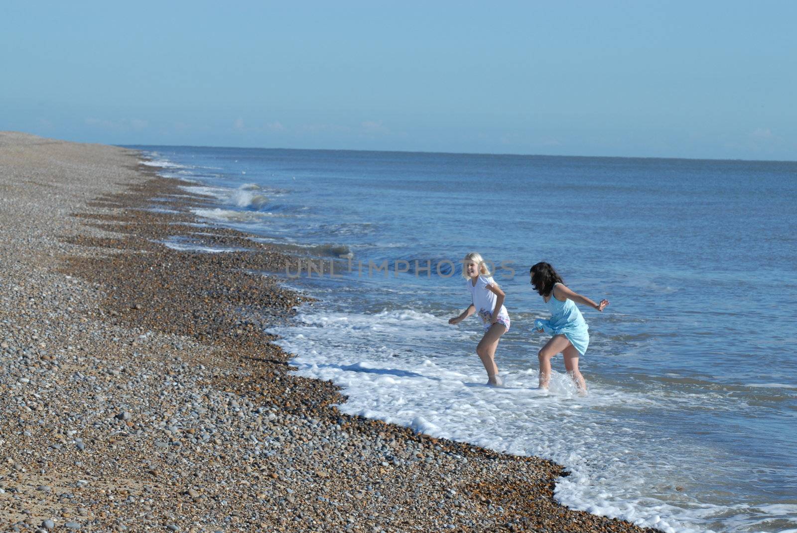 Girls playing on beach by Bildehagen