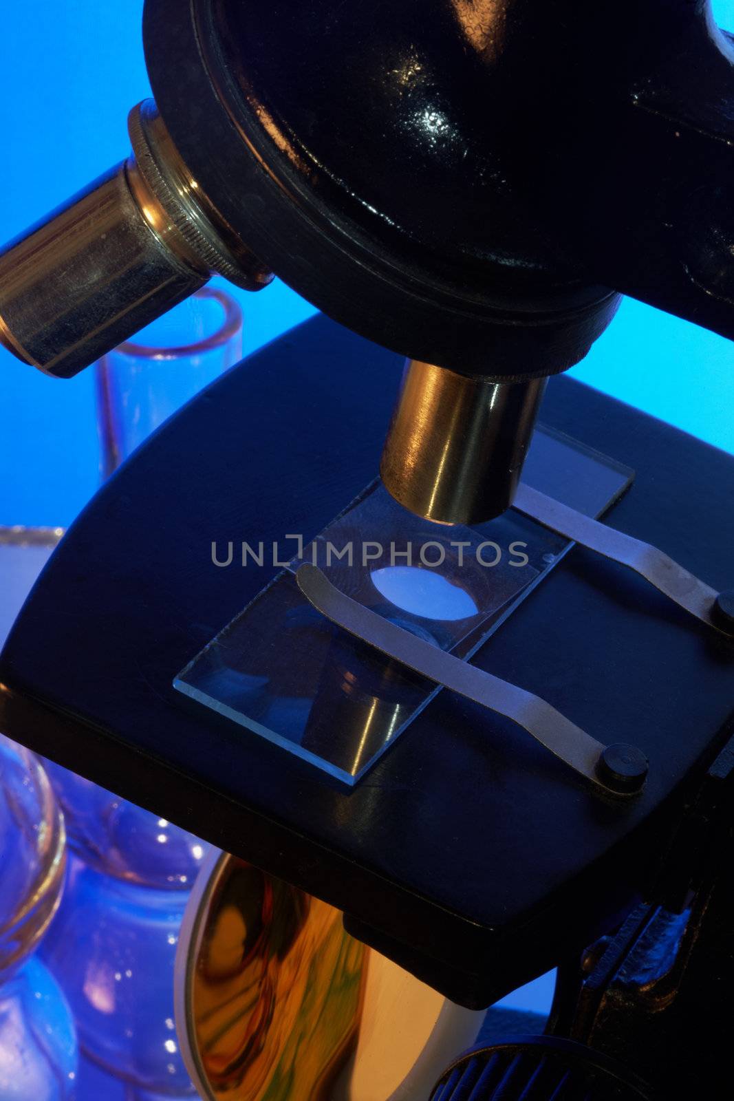 Microscope and laboratory glasswares on a blue background