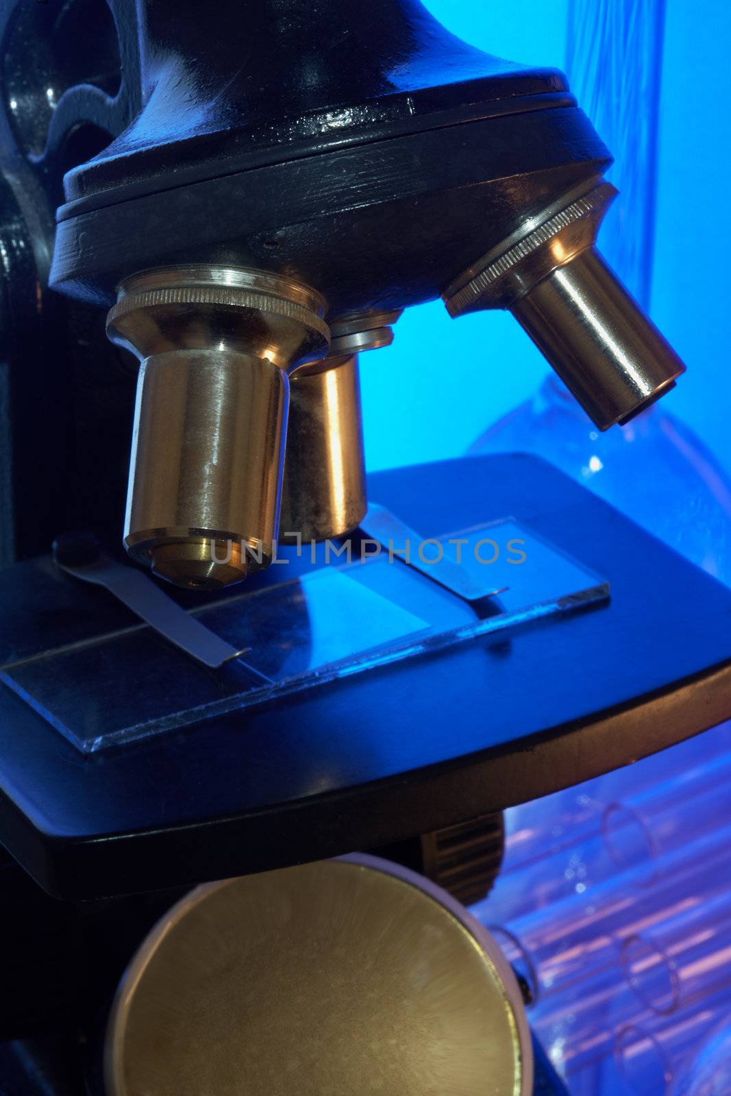 Microscope and laboratory glasswares on a blue background