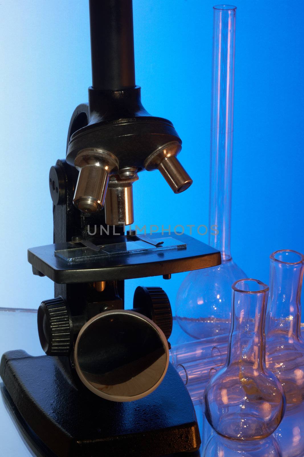 Microscope and laboratory glasswares on a blue background