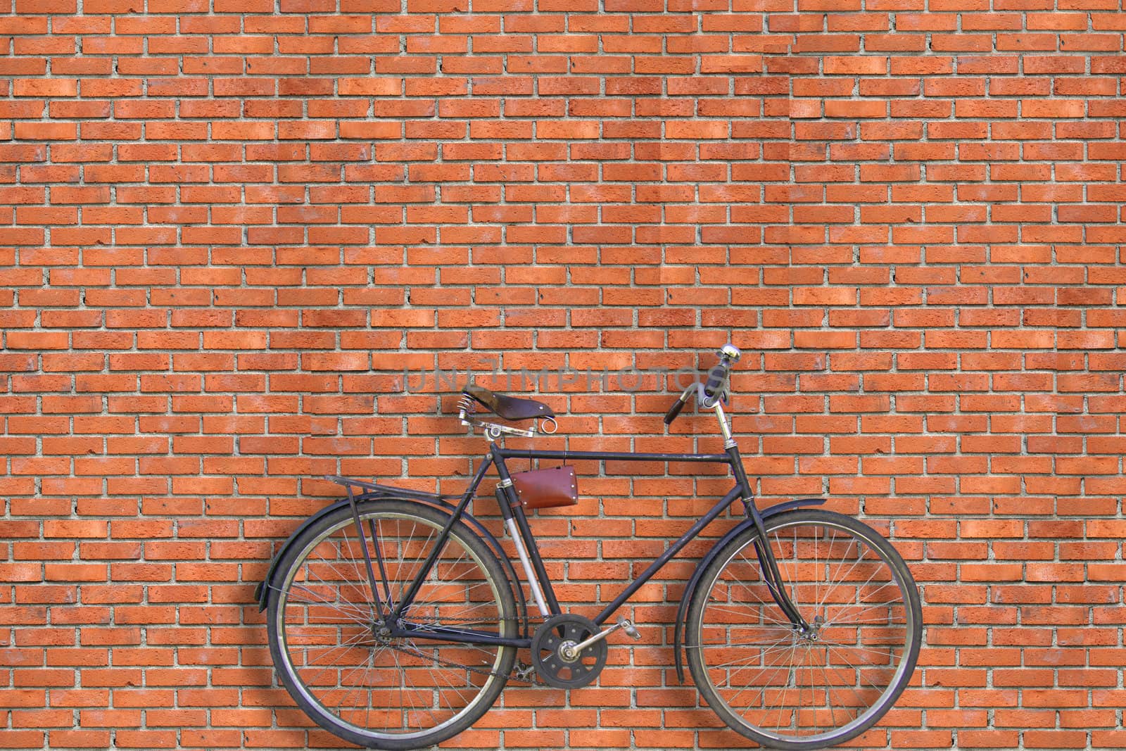 The bicycle stands near a wall from a red brick