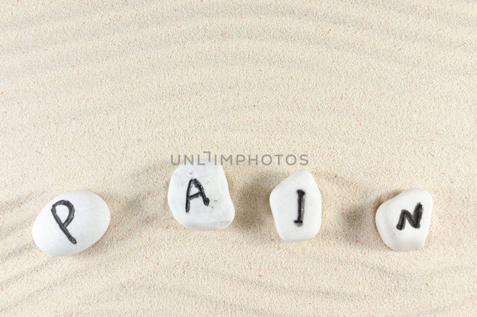Pain word on group of stones with sand background