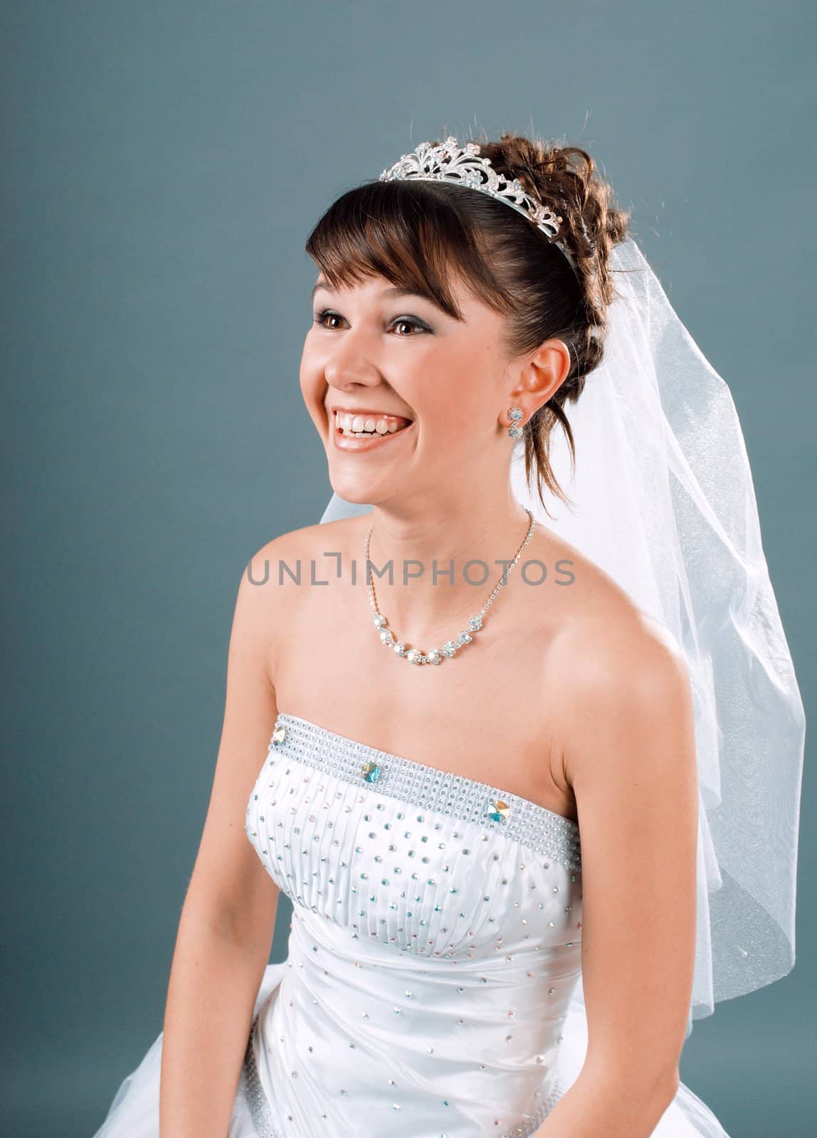 Beauty young bride dressed in elegance white wedding dress  gray studio background 