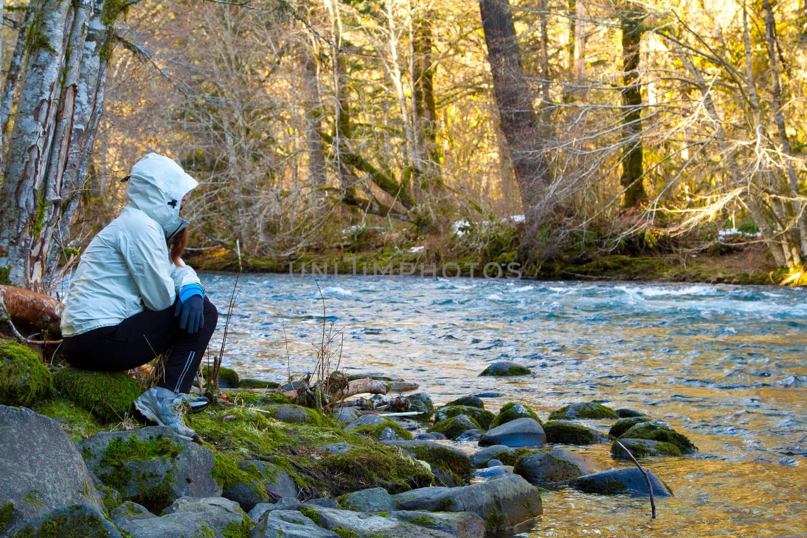 A female hiker takes a rest and looks out over the water of the McKenzie River in Oregon.
