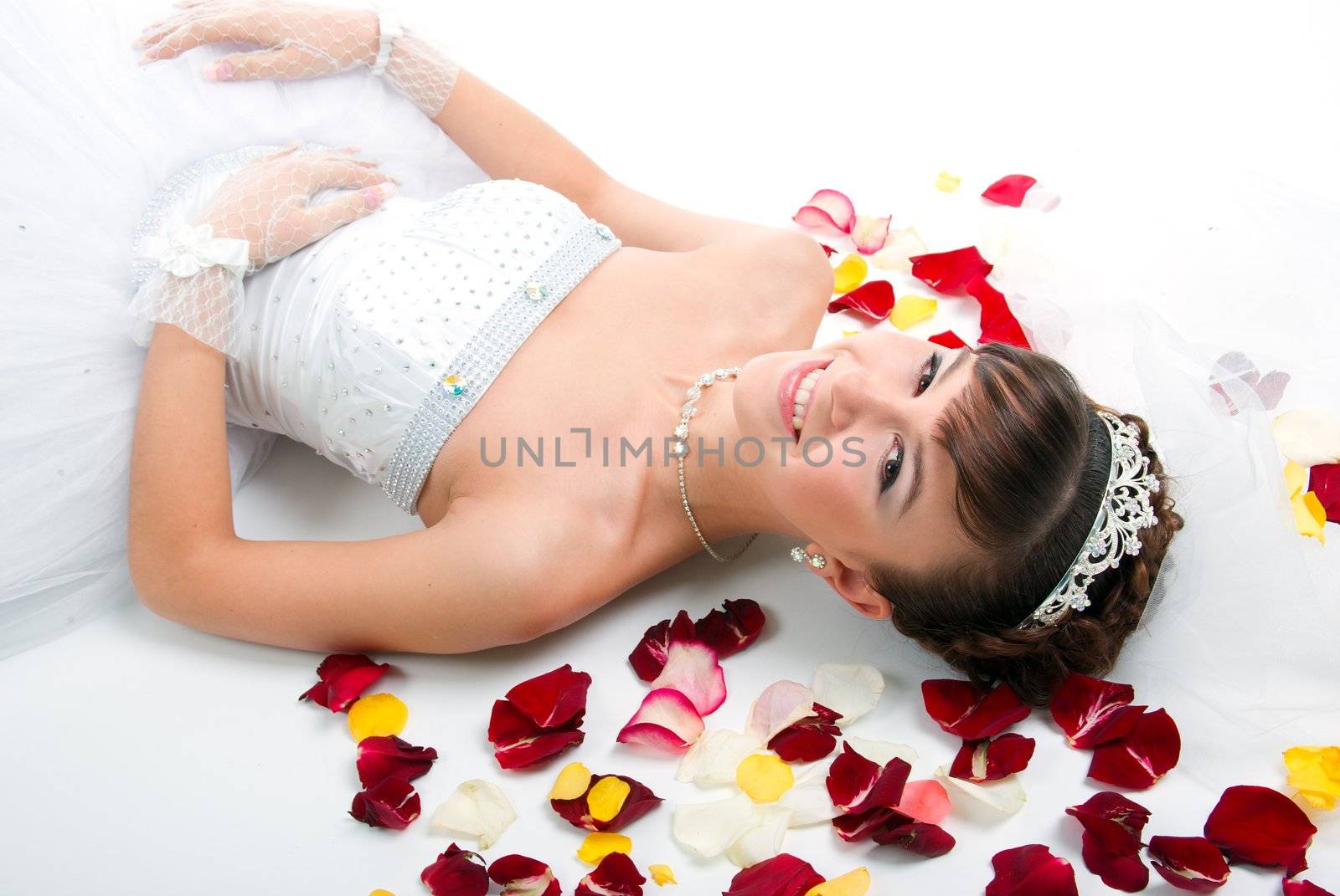 Beautiful sexy bride on  floor among red rose petals on white background 