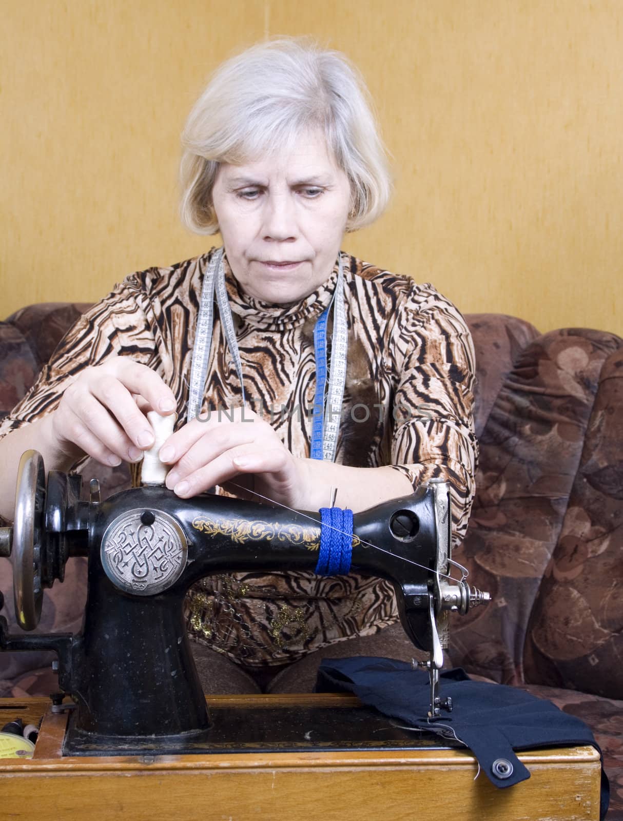 Senior woman using sewing machine at home
