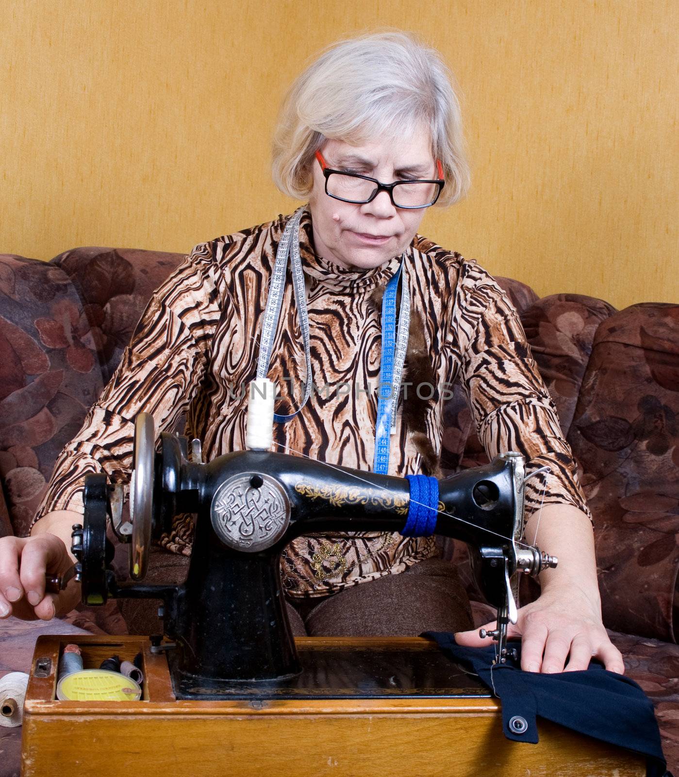 Senior woman using sewing machine at home