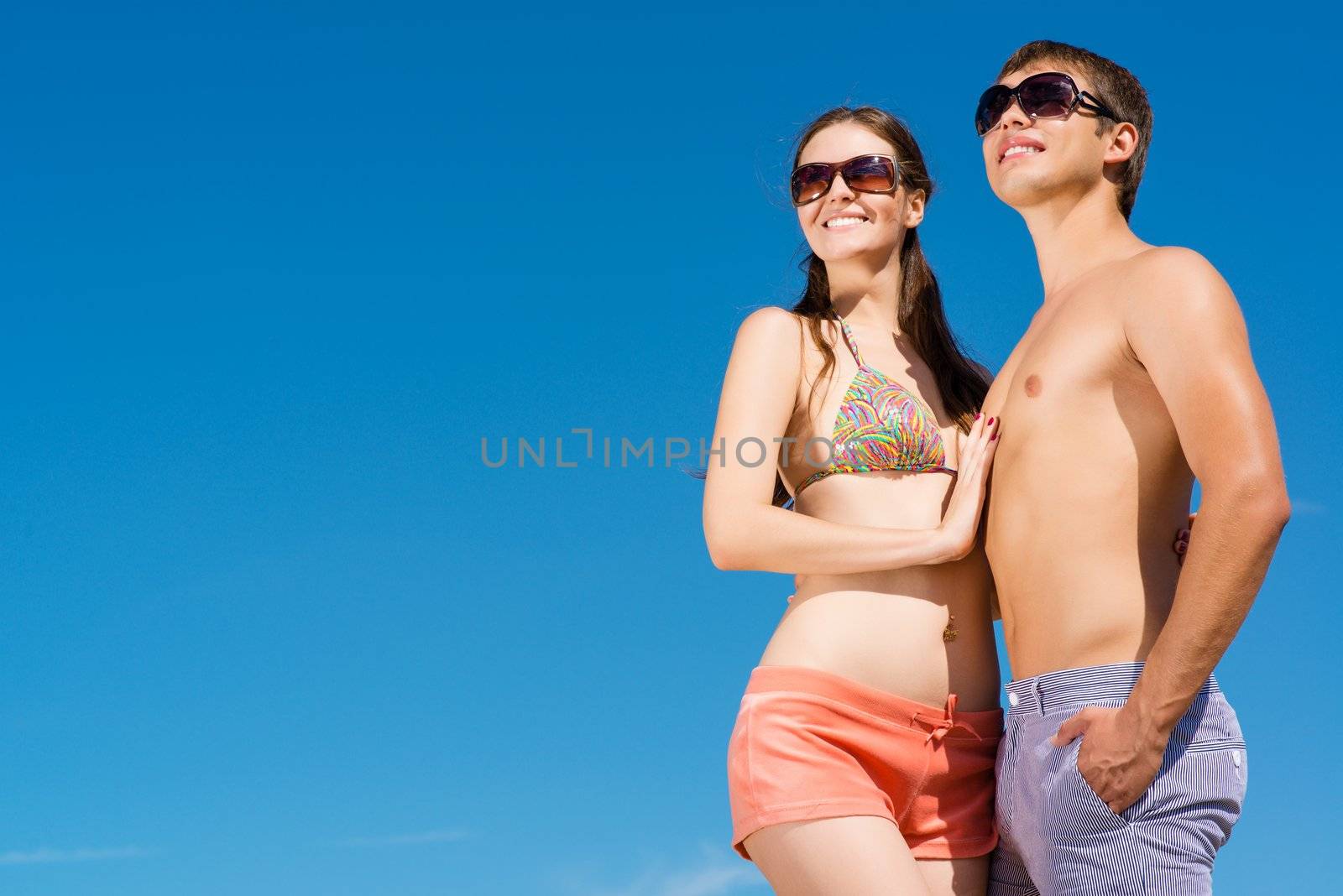 Young couple hugging on a background of blue sky, hold together honeymoon