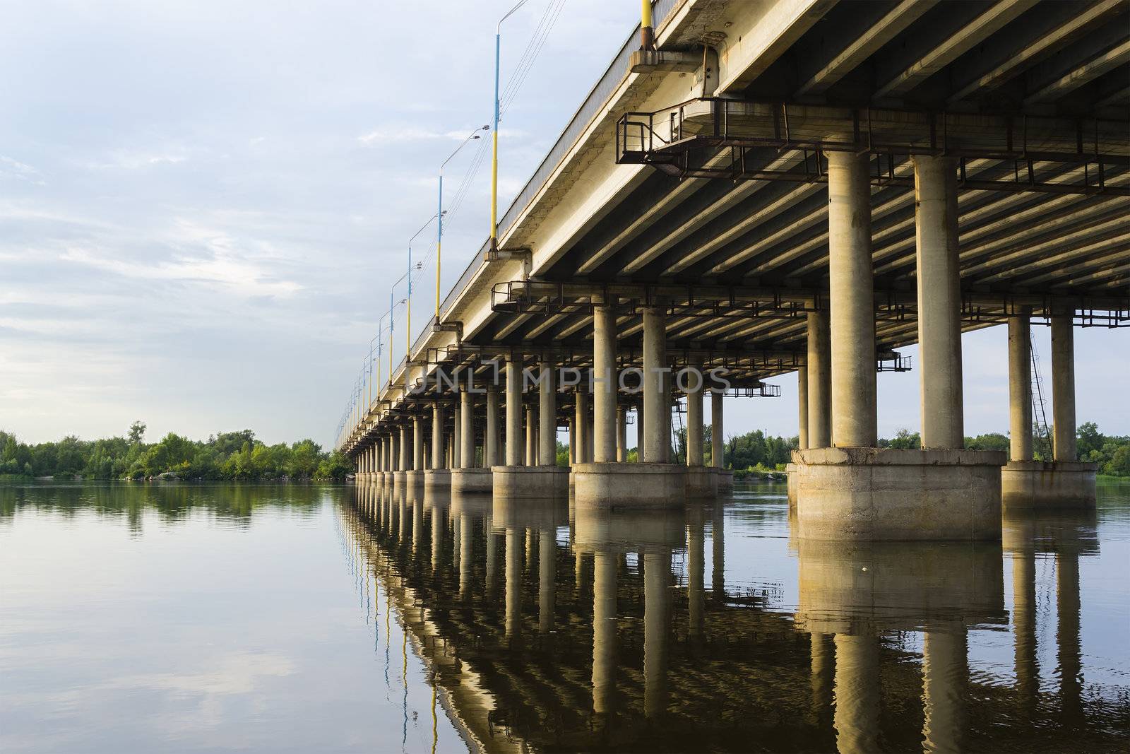 Bridge over a wide river, reflected in the water. View from the bottom side a point.