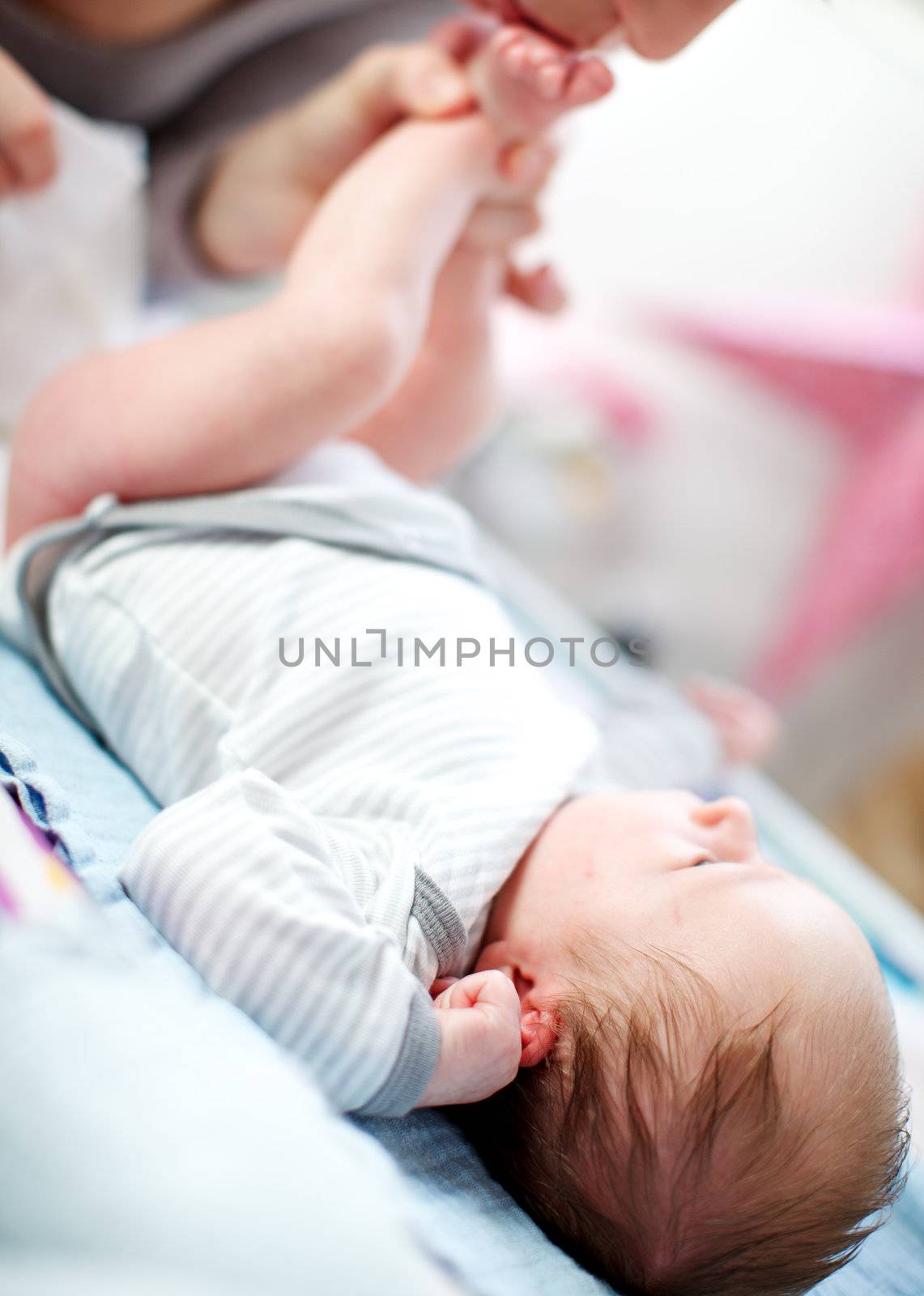 Mother changing a newborn baby's diaper by langstrup