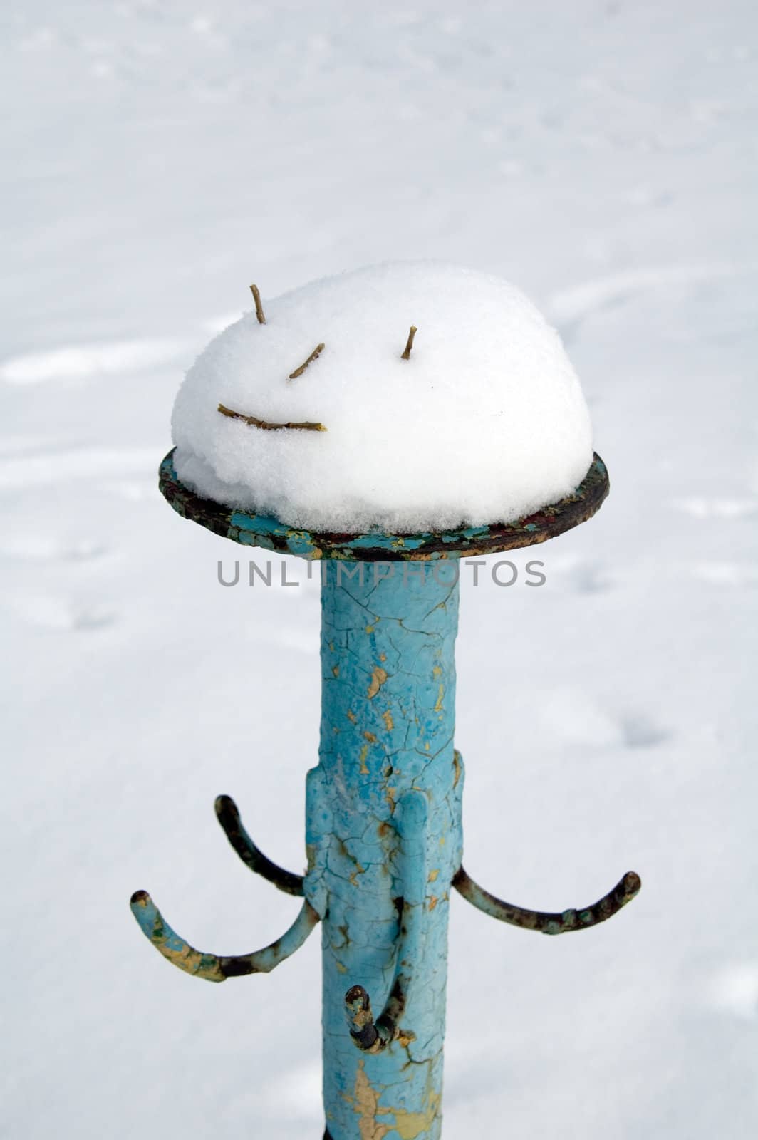Funny abstract character of the snow and reeds on a metal stand