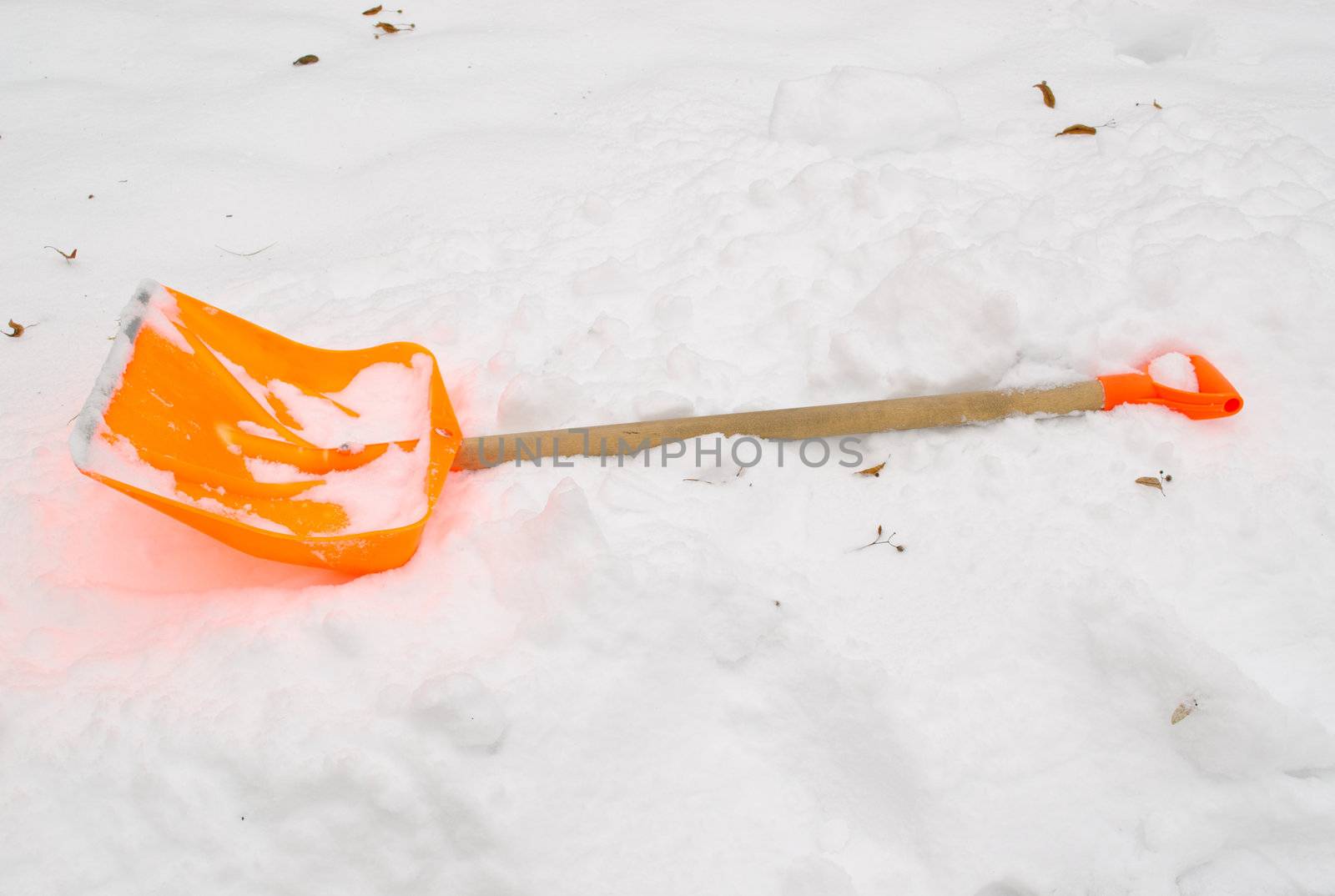 orange plastic snow clean tool lie rest on snowdrift in winter.