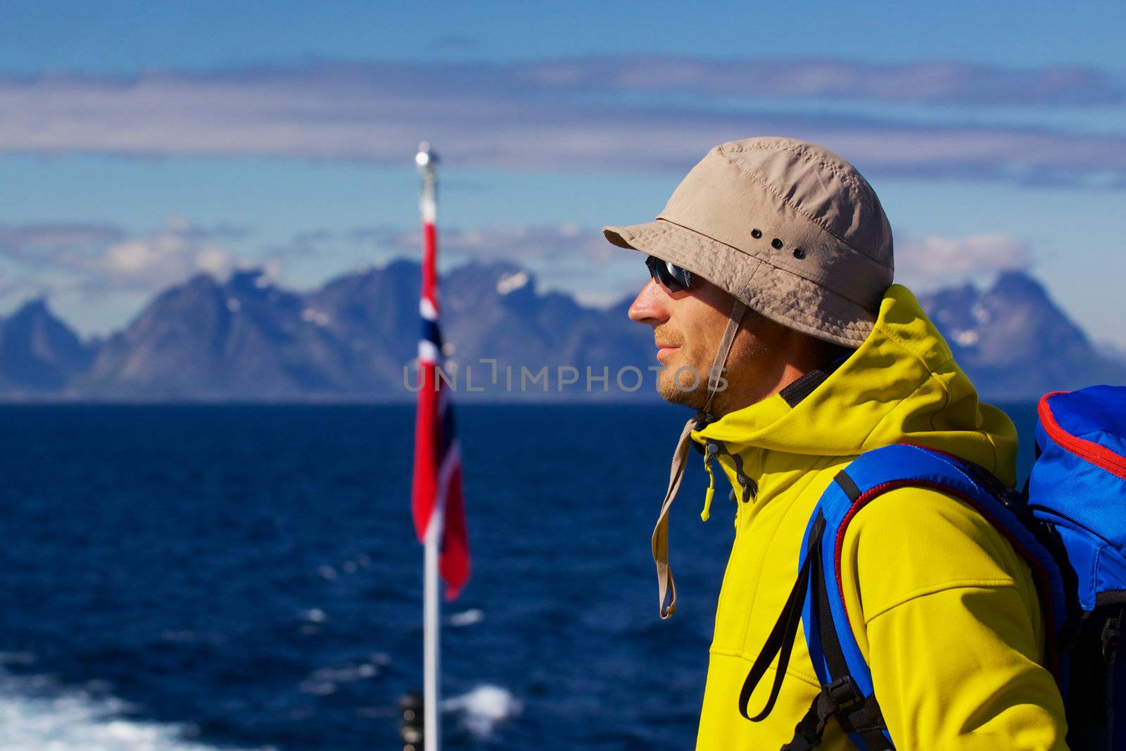 Young man with backpack with panorama of Lofoten islands in Norway in the background