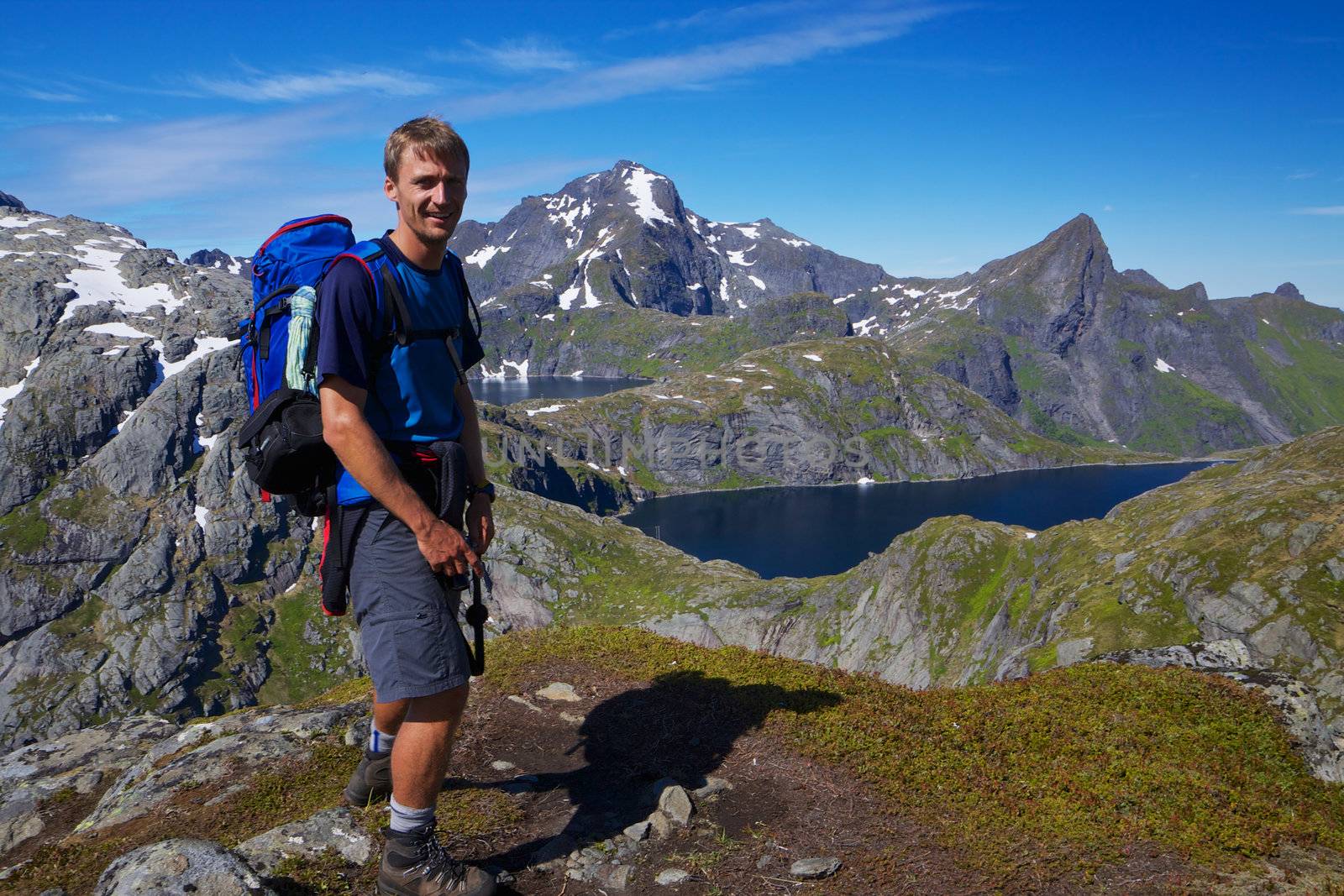 Young active man with backpack hiking on Lofoten islands in Norway on sunny day