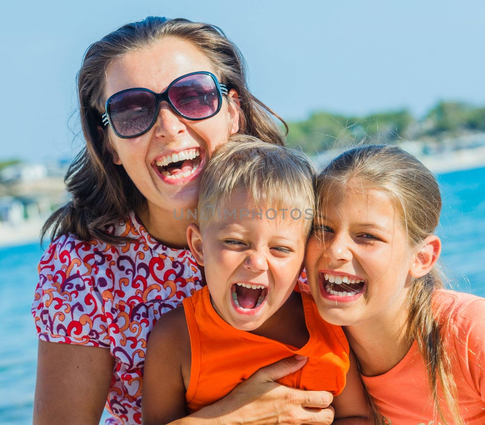 Portrait of happy family laughing and looking at camera on the beach