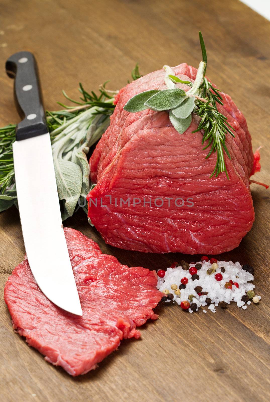 Raw beef on wooden table with rosemary ,sage and salt