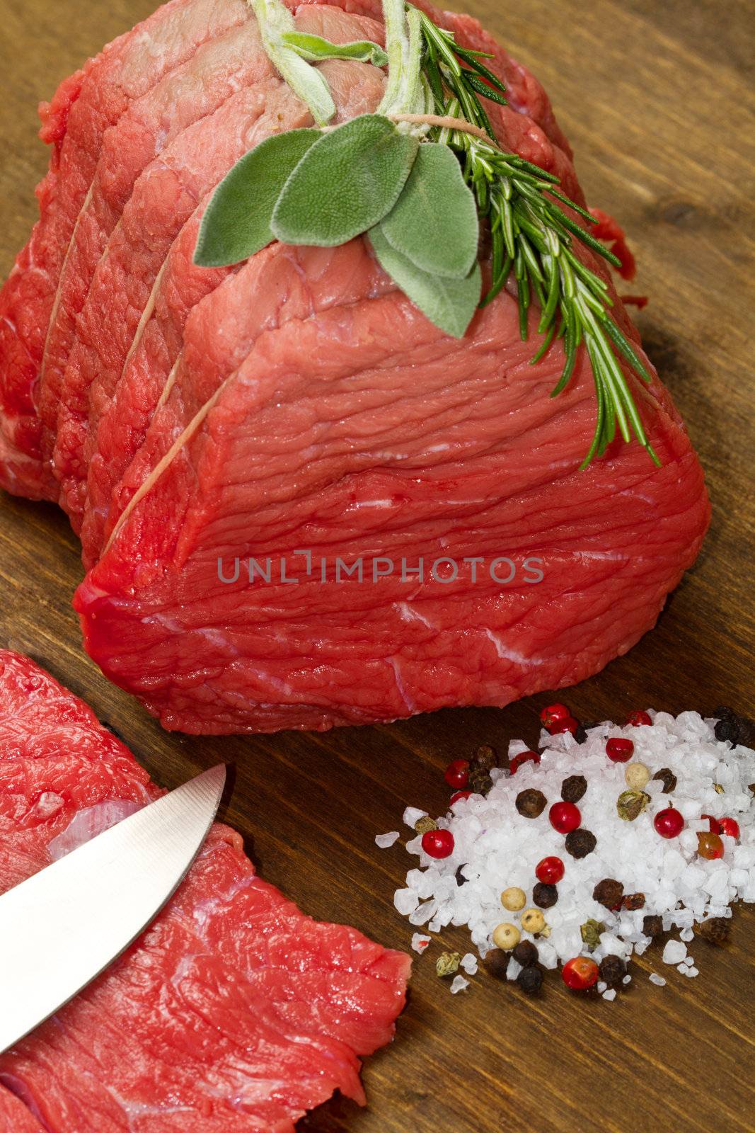 Raw beef on wooden table with rosemary ,sage and salt