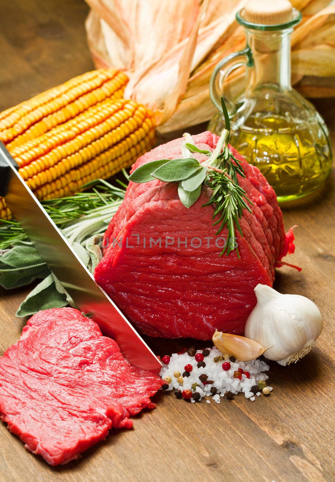Raw beef on wooden table with rosemary ,sage , salt, cob and garlic
