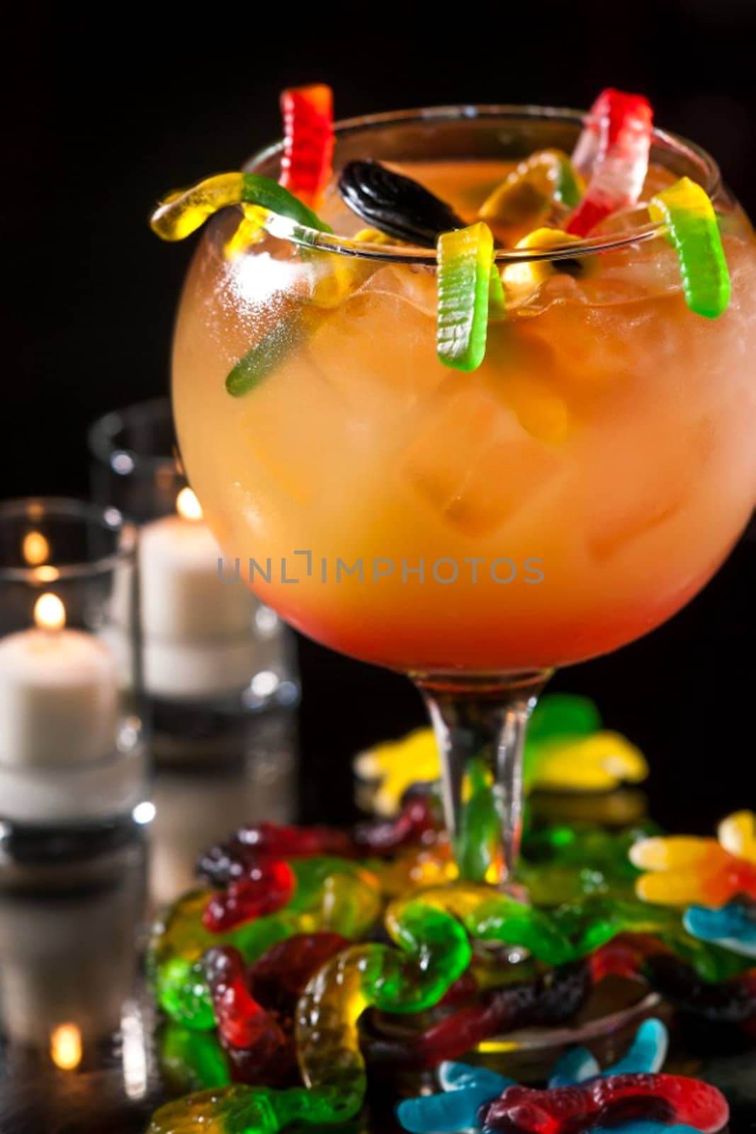 orange cocktail with funny jelly worms on black background