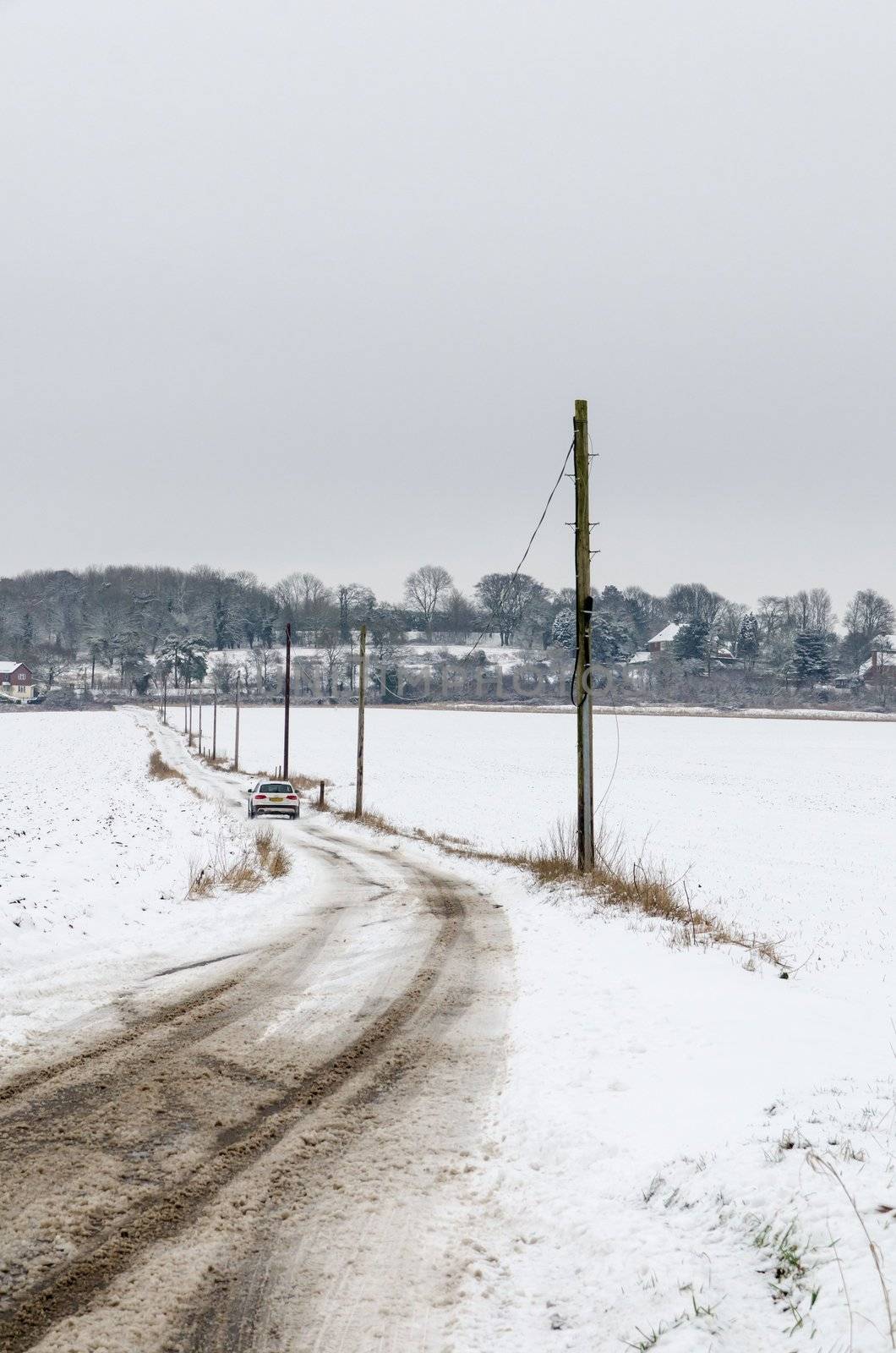 White car driving along a snow covered road