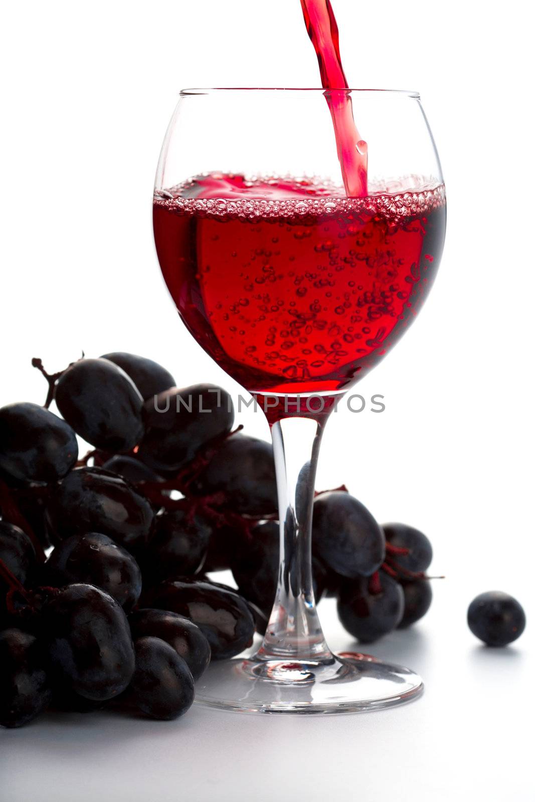 grapes and red wine in a glass isolated on white background
