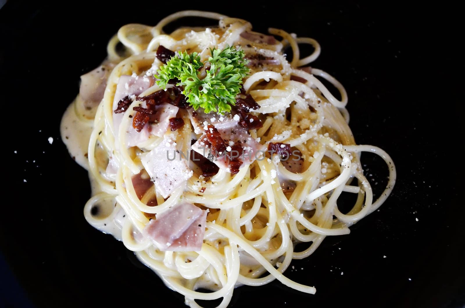 Spaghetti with ham isolated in black plate