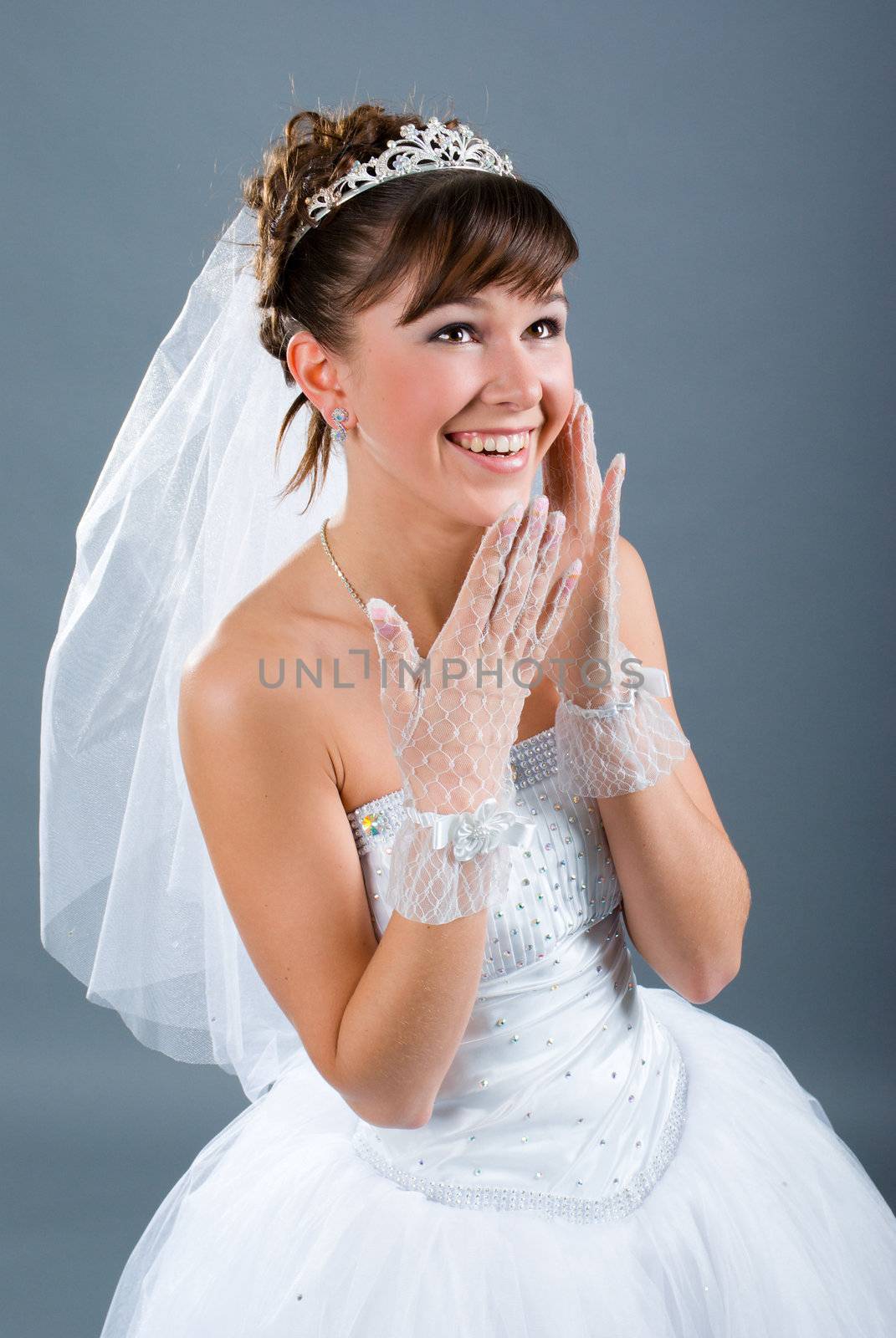 Beauty young bride dressed in elegance white wedding dress  gray studio background 