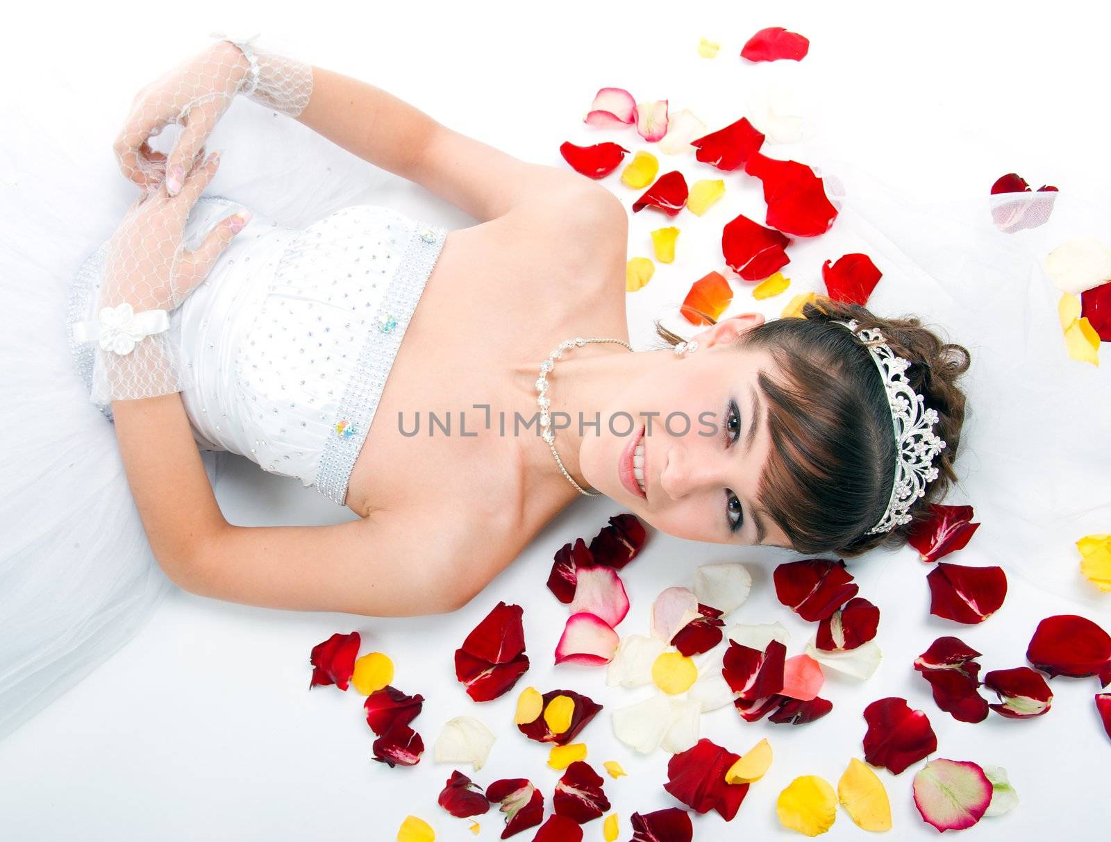 Beautiful sexy bride on  floor among red rose petals on white background 