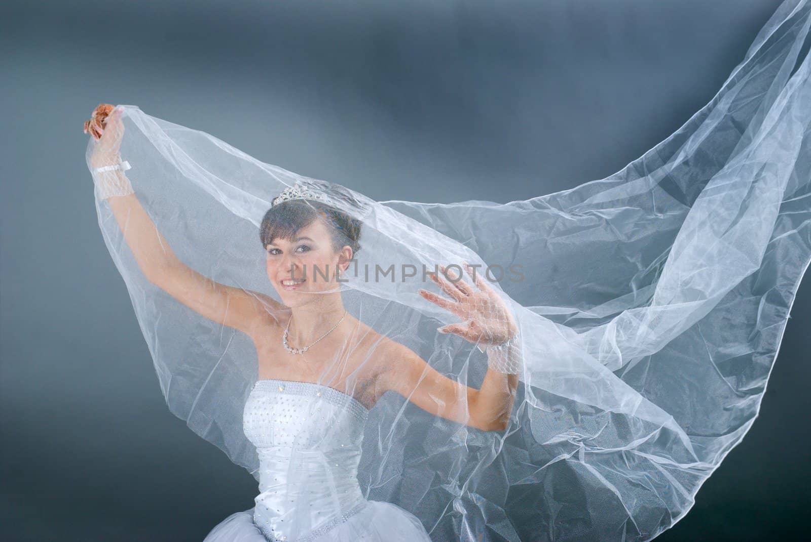 Beauty young bride dressed in elegance white wedding dress  gray studio background 