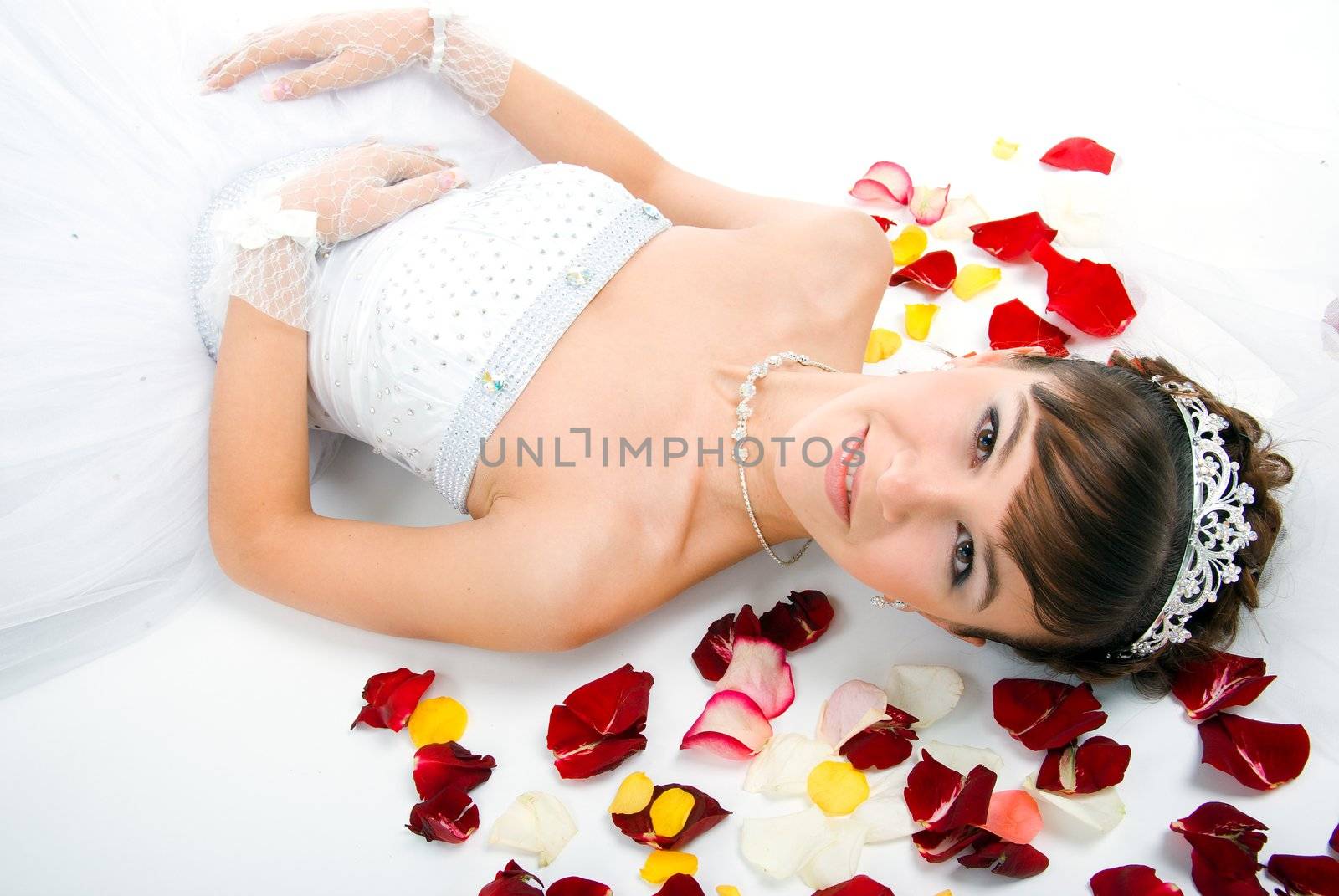 Beautiful sexy bride on  floor among red rose petals on white background 