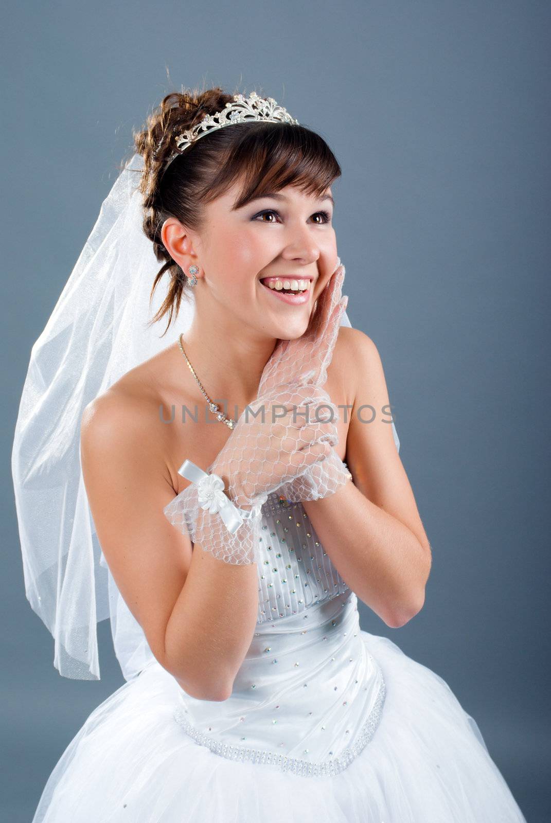 Beauty young bride dressed in elegance white wedding dress  gray studio background 