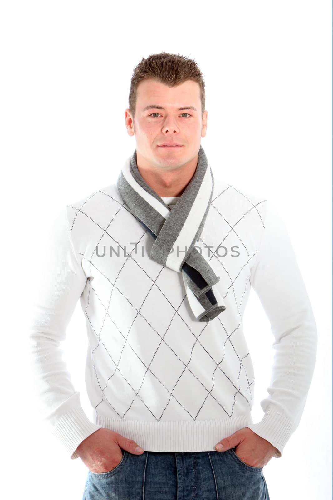 Handsome fashionable man in a winter outfit with a trendy scarf standing facing the camera with his hands in his pockets isolated on white