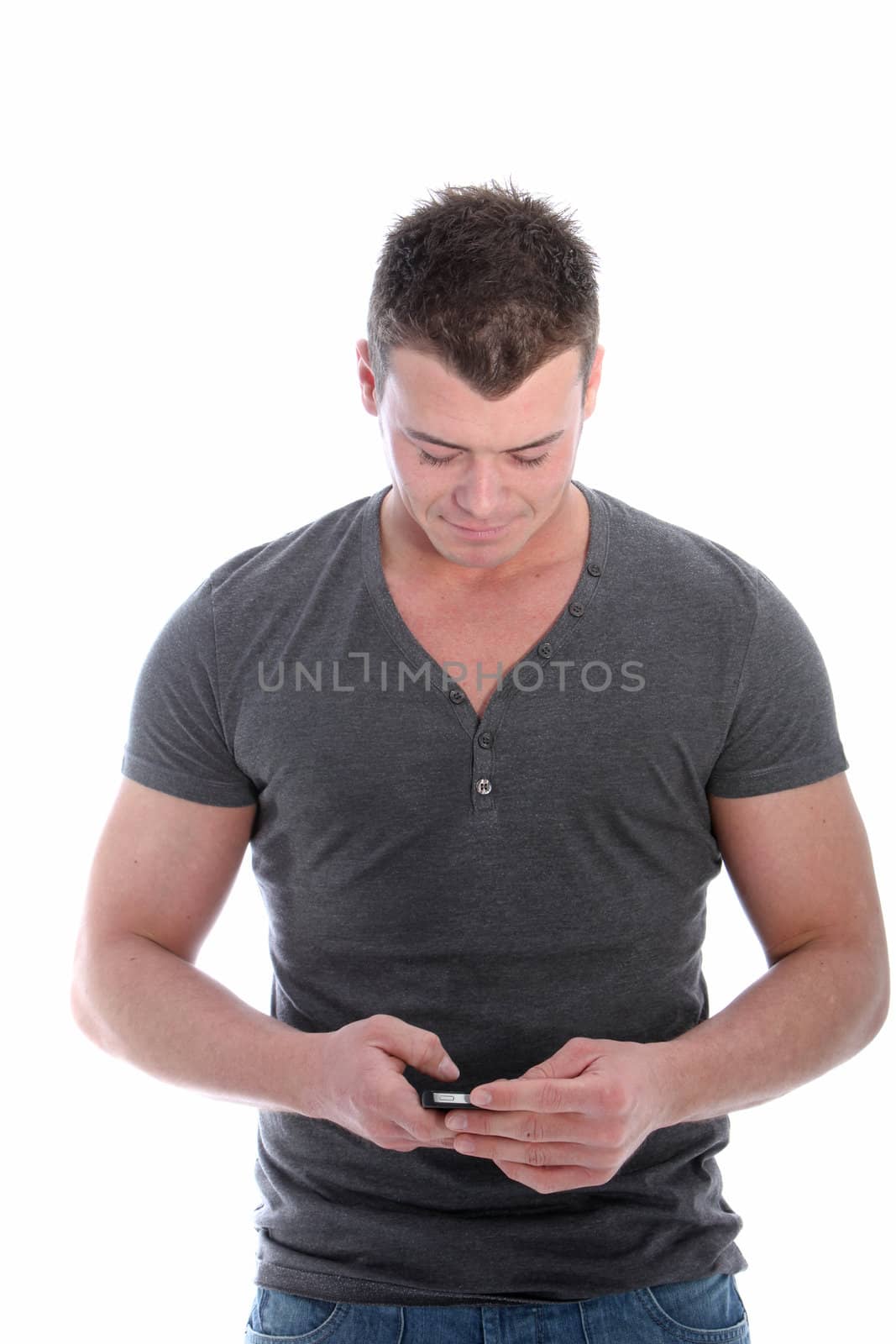 Fit handsome man texting on his mobile looking down as he types on the touchscreen, three quarter studio portrait on white