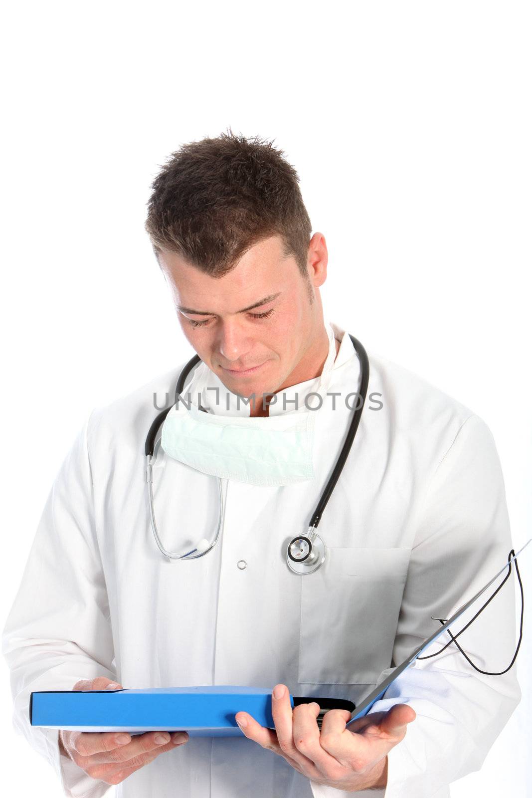 Young male medical doctor in a labcoat with a stethoscope around his neck standing consulting his notes isolated on white