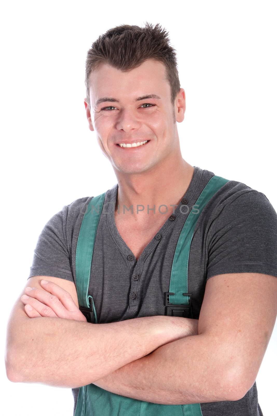 Charismatic genial male artisan or technician standing with his arms folded wearing dungarees grinning at the camera isolated on white
