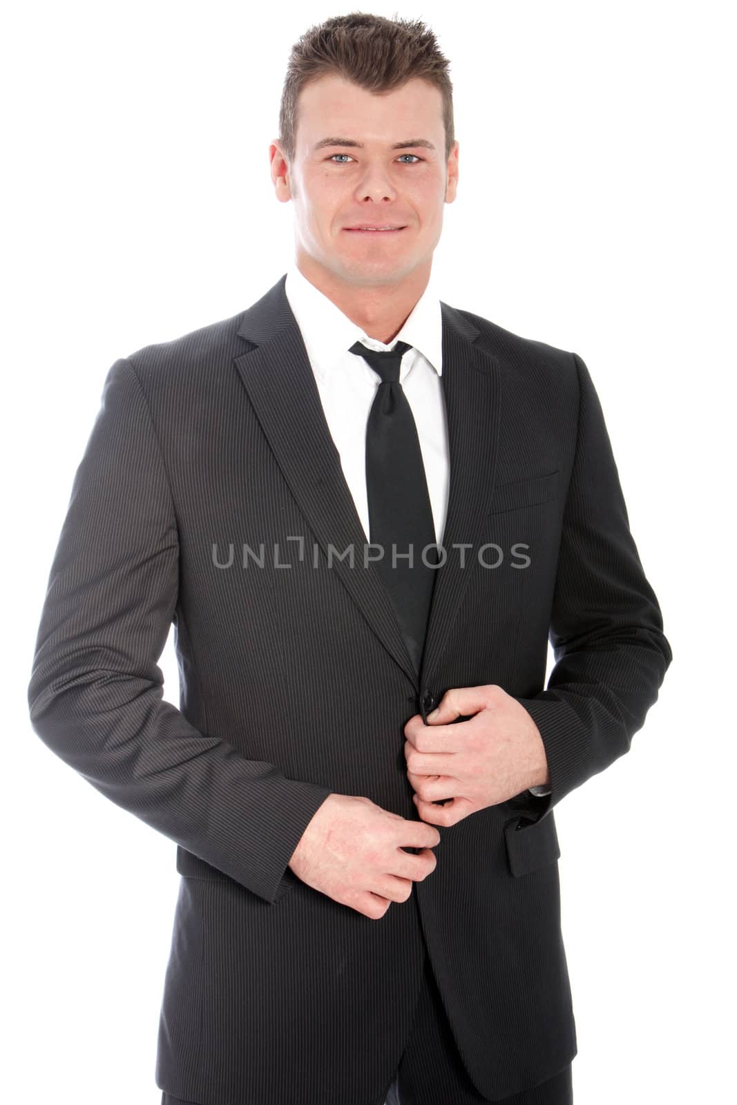 Dapper handsome young businessman in a classical black suit standing looking at the camera, three quarter portrait on white