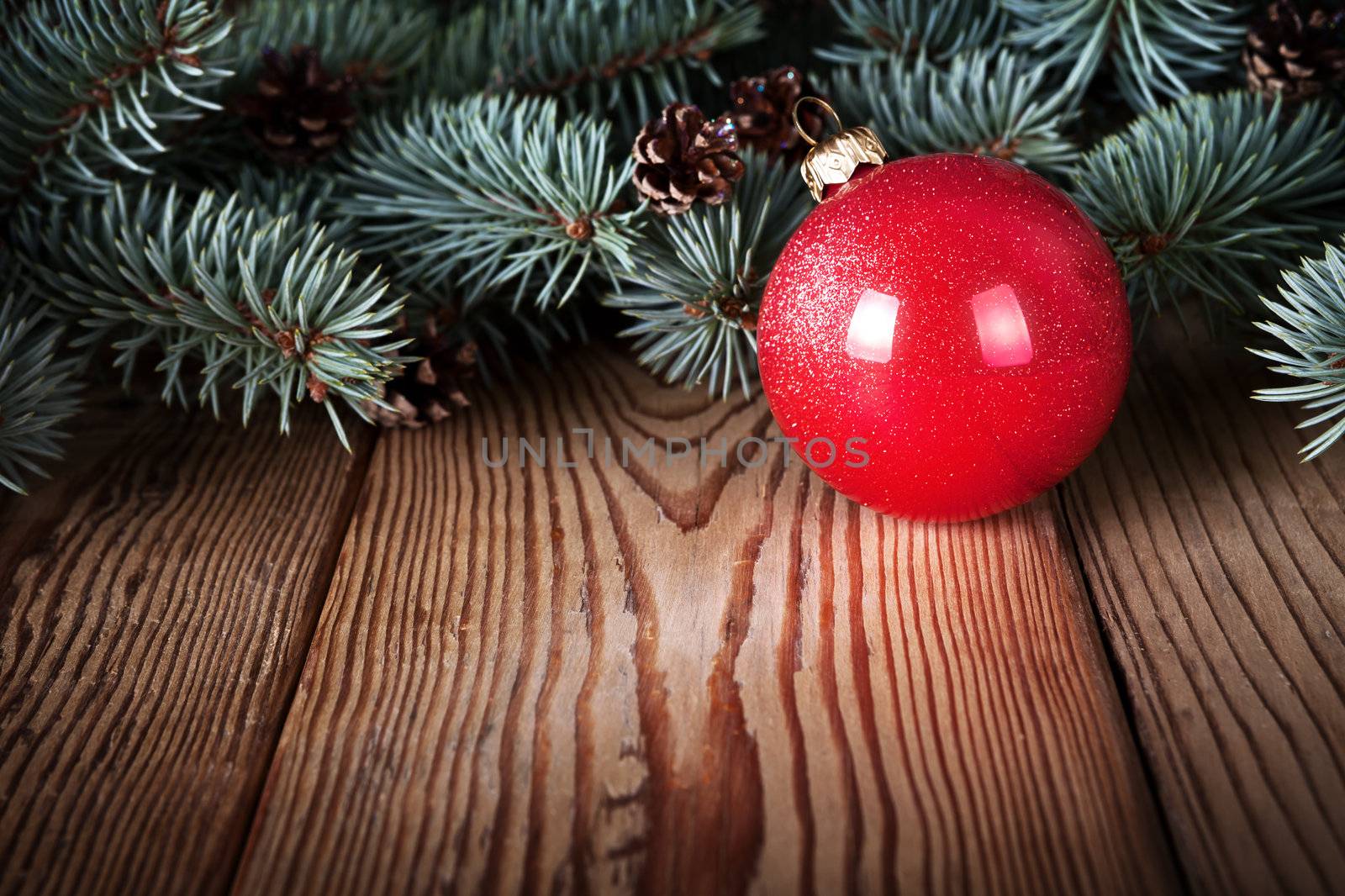Red christmas ball on wooden background with branches of pine wood. Copy space