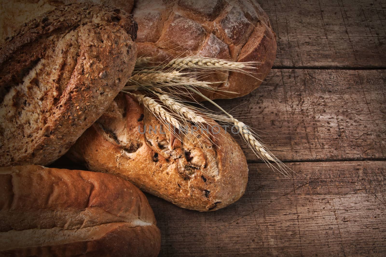 Assortment of loaves of bread on wood by Sandralise